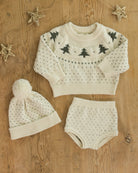 Knitted baby set with sweater, hat, and shorts on a wooden surface