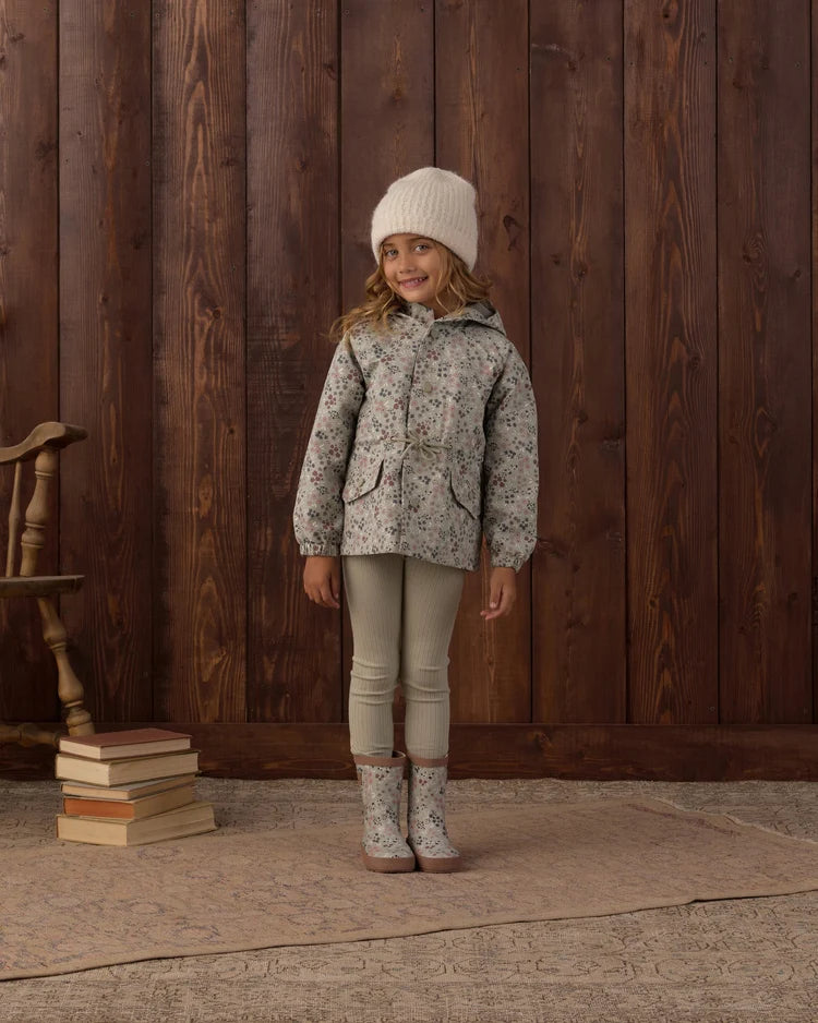 A child wearing the Rylee + Cru Garden Raincoat featuring a cheerful botanical print in a soft sage hue paired with sage-colored leggings.