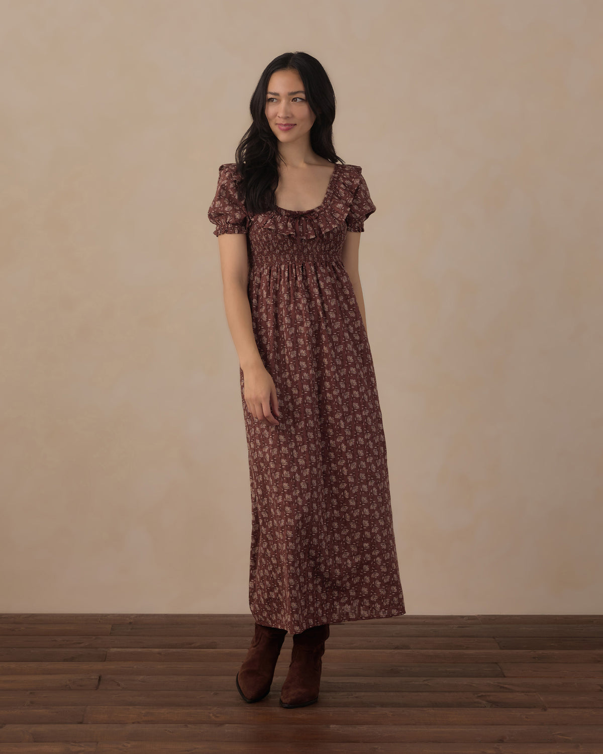 Woman wearing a brown floral dress against a beige background
