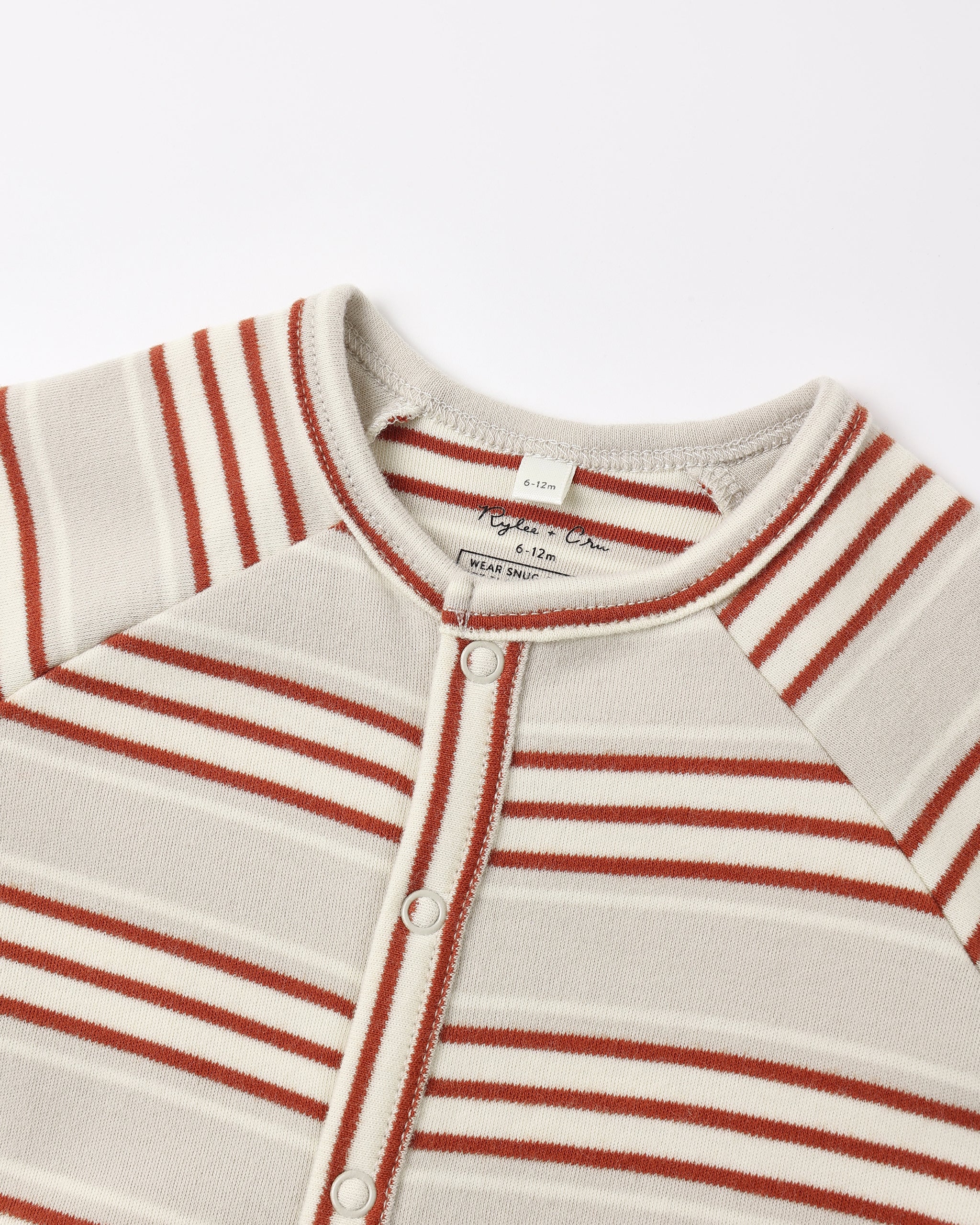 Close-up of a striped baby henley top with a button-down front, featuring horizontal rust red and cream stripes on a light beige knit fabric.