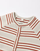 Close-up of a striped baby henley top with a button-down front, featuring horizontal rust red and cream stripes on a light beige knit fabric.