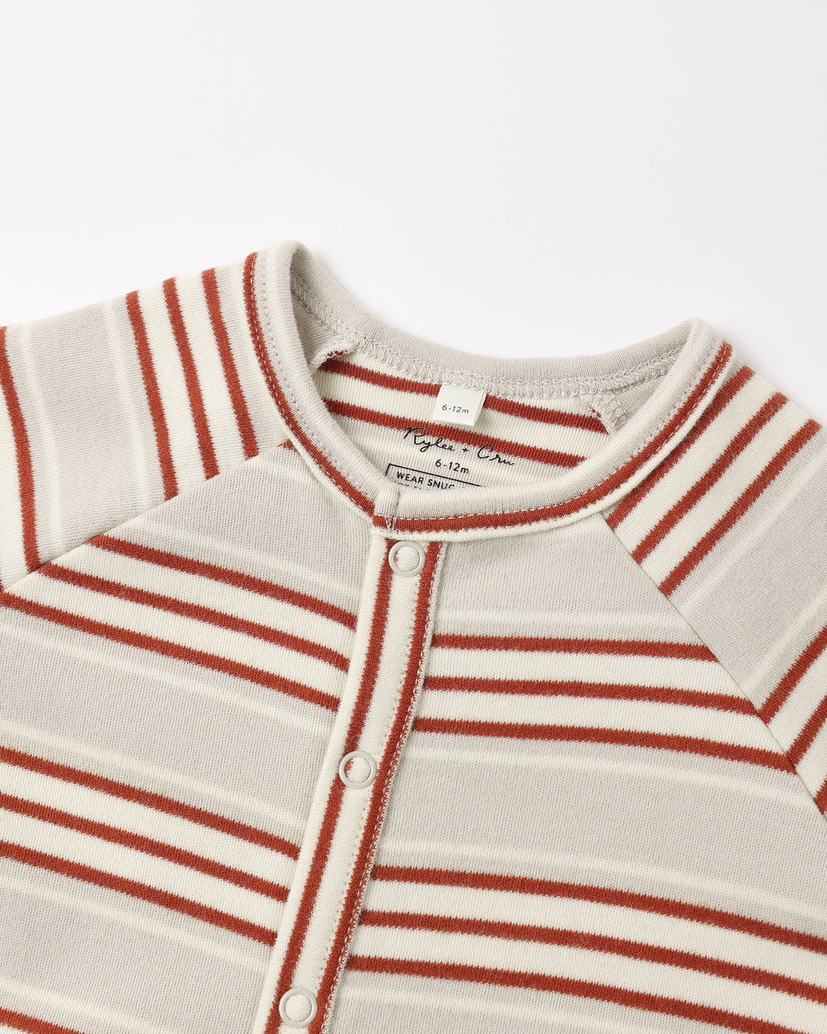 Close-up of a striped baby henley top with a button-down front, featuring horizontal rust red and cream stripes on a light beige knit fabric.