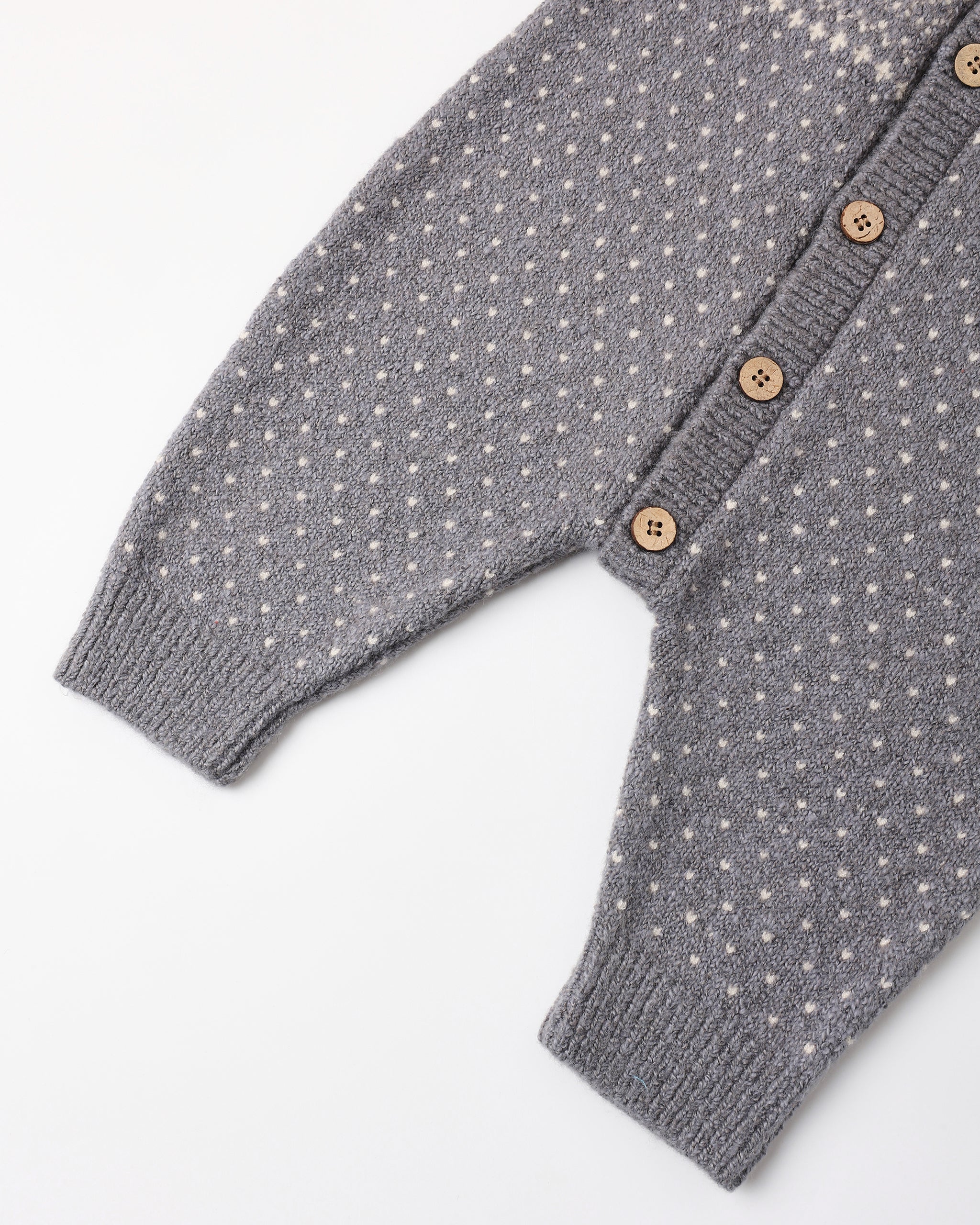 The image shows a light blue or slate-colored knitted baby onesie or romper with a textured dot pattern front button closure.
