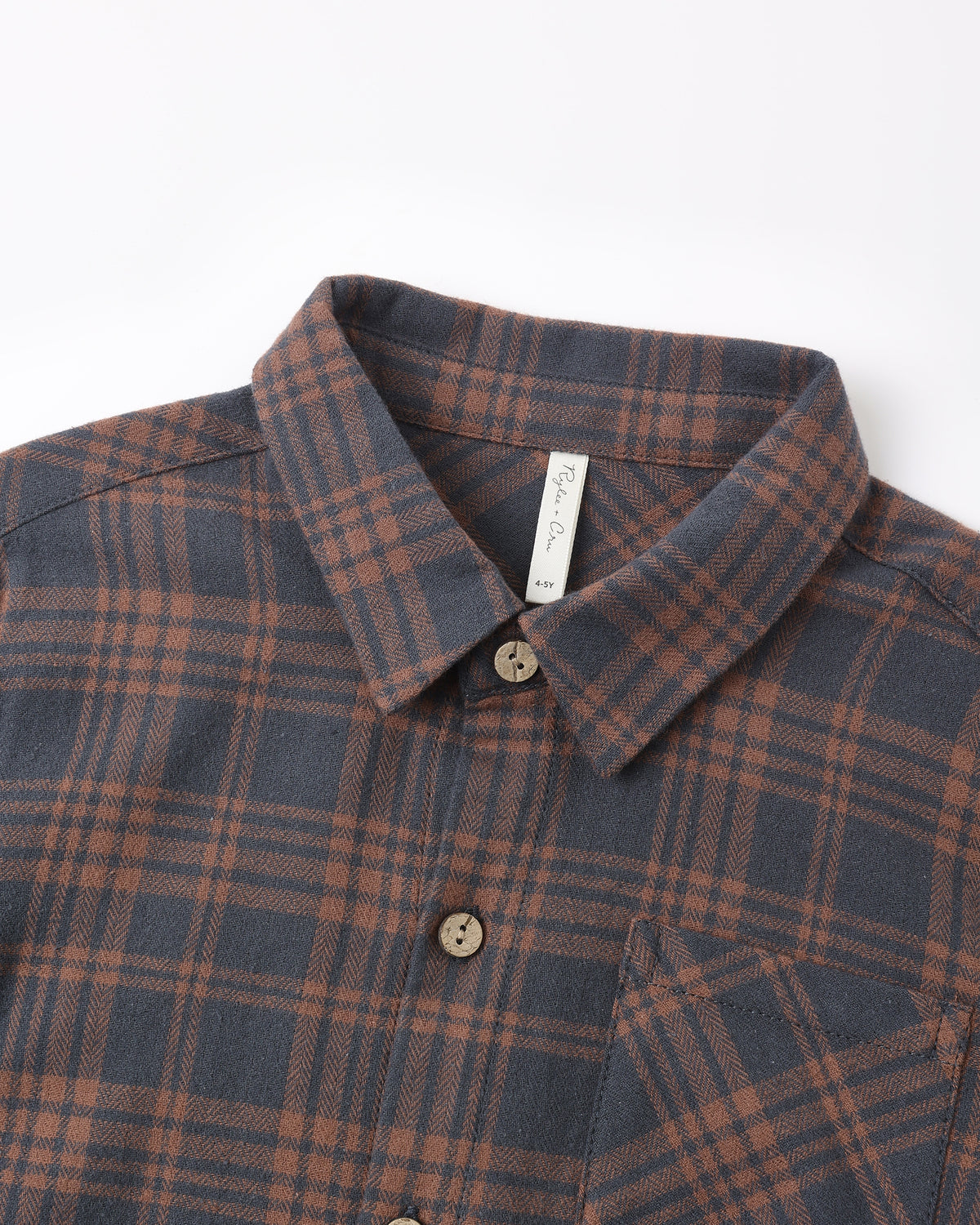 A close-up of a plaid button-down shirt collar and upper chest. The fabric has a dark slate blue-gray base with a rust brown and muted orange plaid pattern.