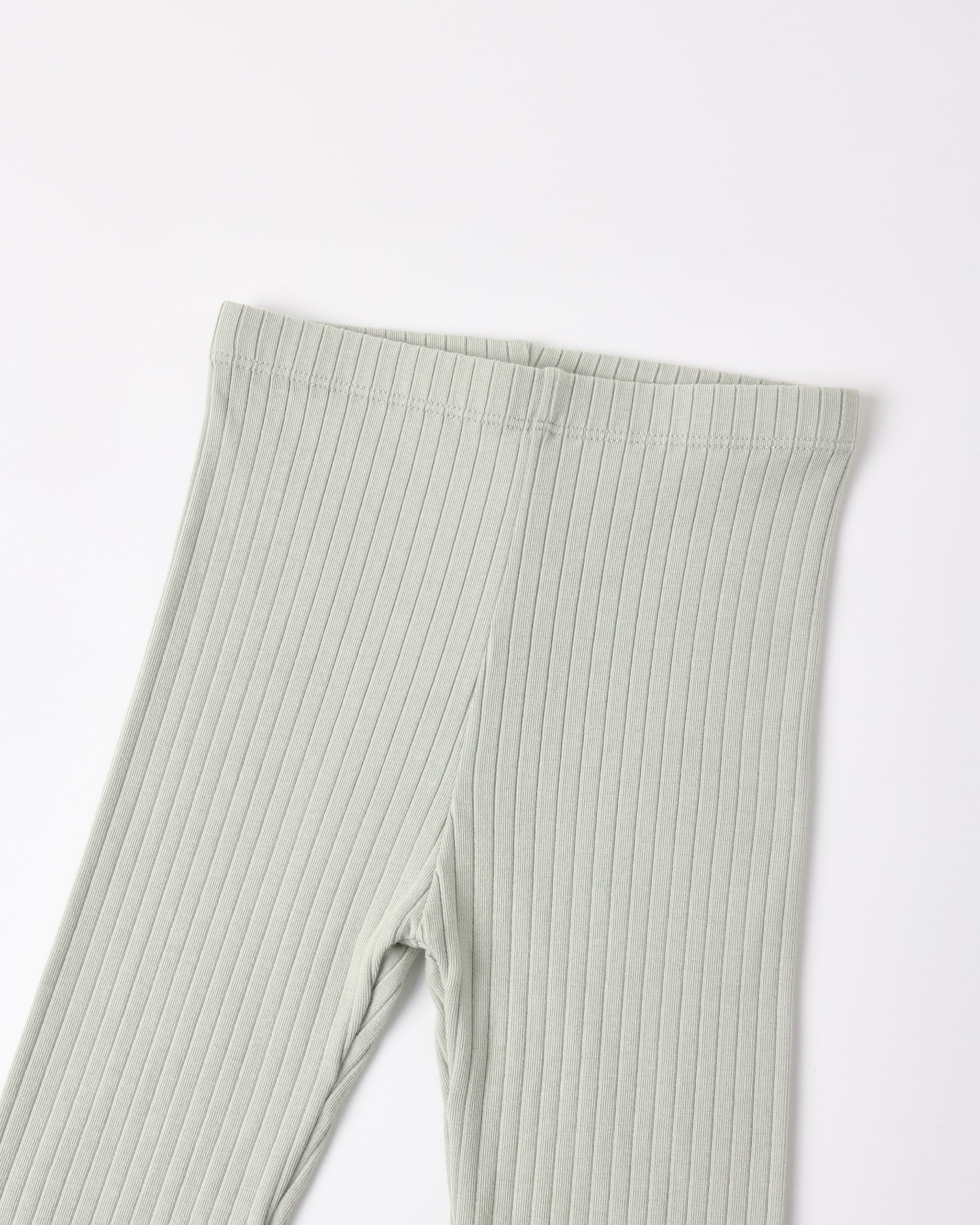 A close-up of ribbed knit leggings in a light sage green color, showing the texture and waistband detail against a plain white background.