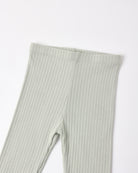A close-up of ribbed knit leggings in a light sage green color, showing the texture and waistband detail against a plain white background.