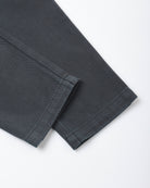 A close-up of folded dark charcoal gray fabric, showing the texture and hem detail against a clean white background.