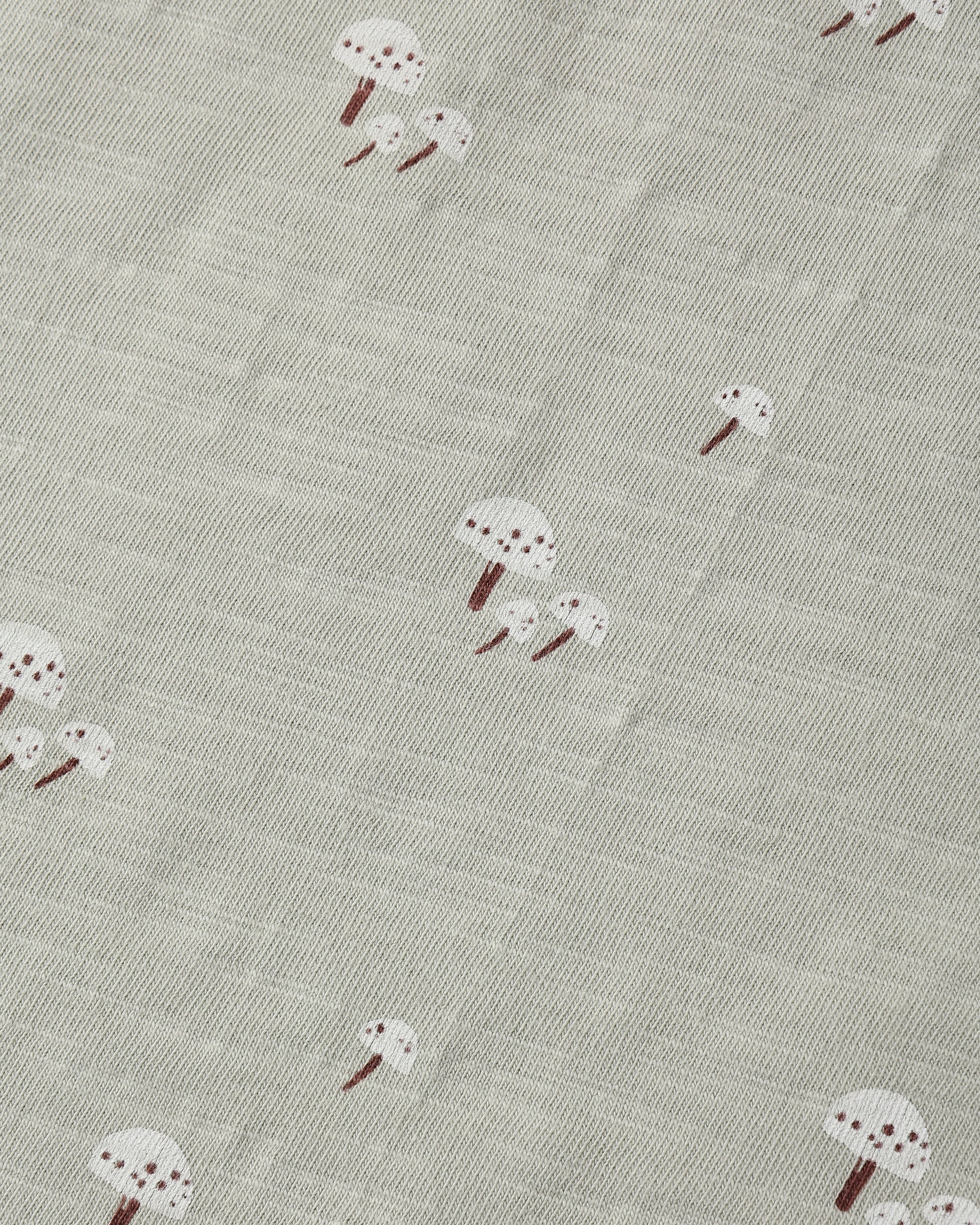 A close-up of a textured fabric featuring a repeating pattern of small white mushrooms with brown stems on a light gray-beige background.
