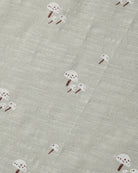 A close-up of a textured fabric featuring a repeating pattern of small white mushrooms with brown stems on a light gray-beige background.