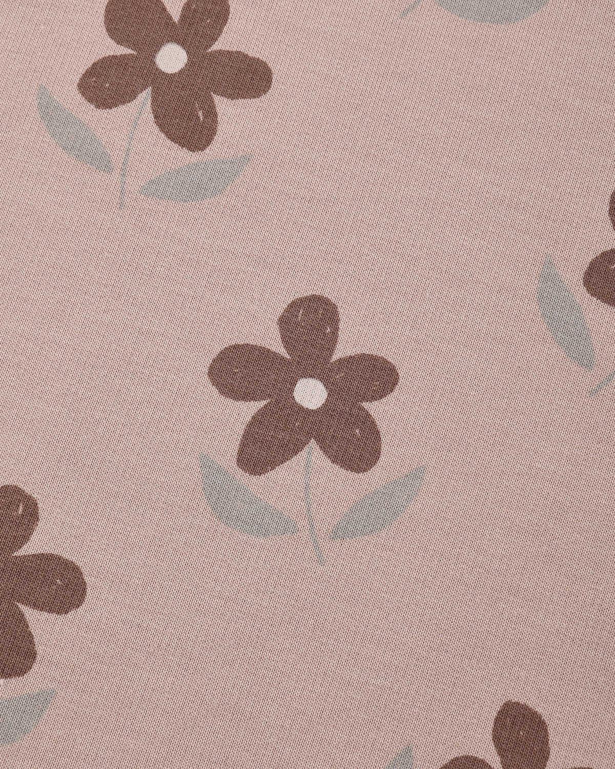 A close-up of a dusty pink fabric with a repeating pattern of dark brown flowers and light gray-green leaves.
