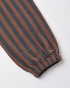A close-up of a striped fabric product, likely a sweatshirt sleeve or pants leg, featuring alternating brown and dark charcoal gray vertical stripes with a gathered elastic cuff.