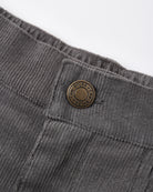 Close-up of dark gray corduroy trousers showing the waistband, button closure, and ribbed fabric texture against a white background.