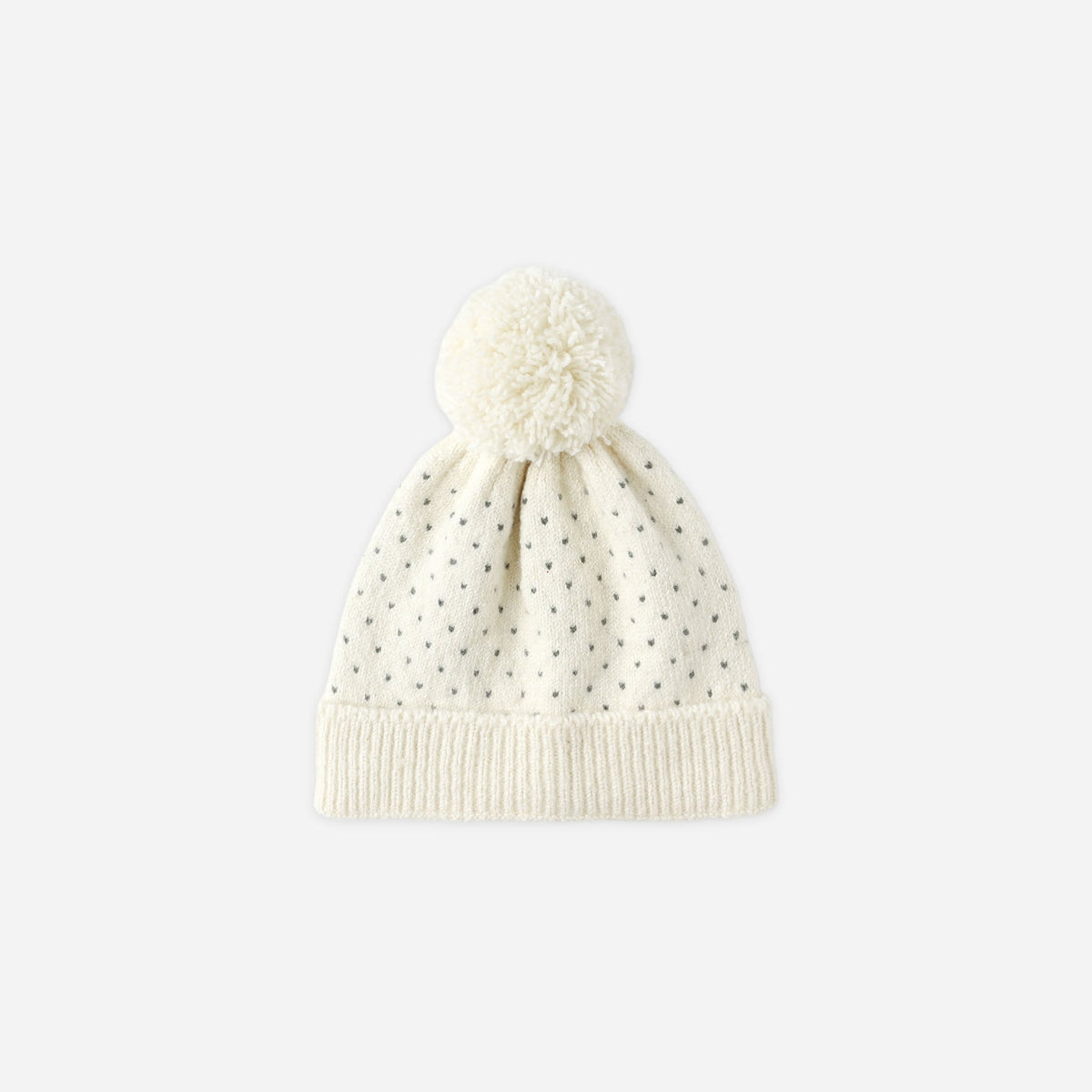 White knit beanie with pom-pom on a light beige background