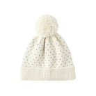 An off-white knit pom-pom beanie with a small black polka dot pattern and a ribbed brim, shown against a plain white background.