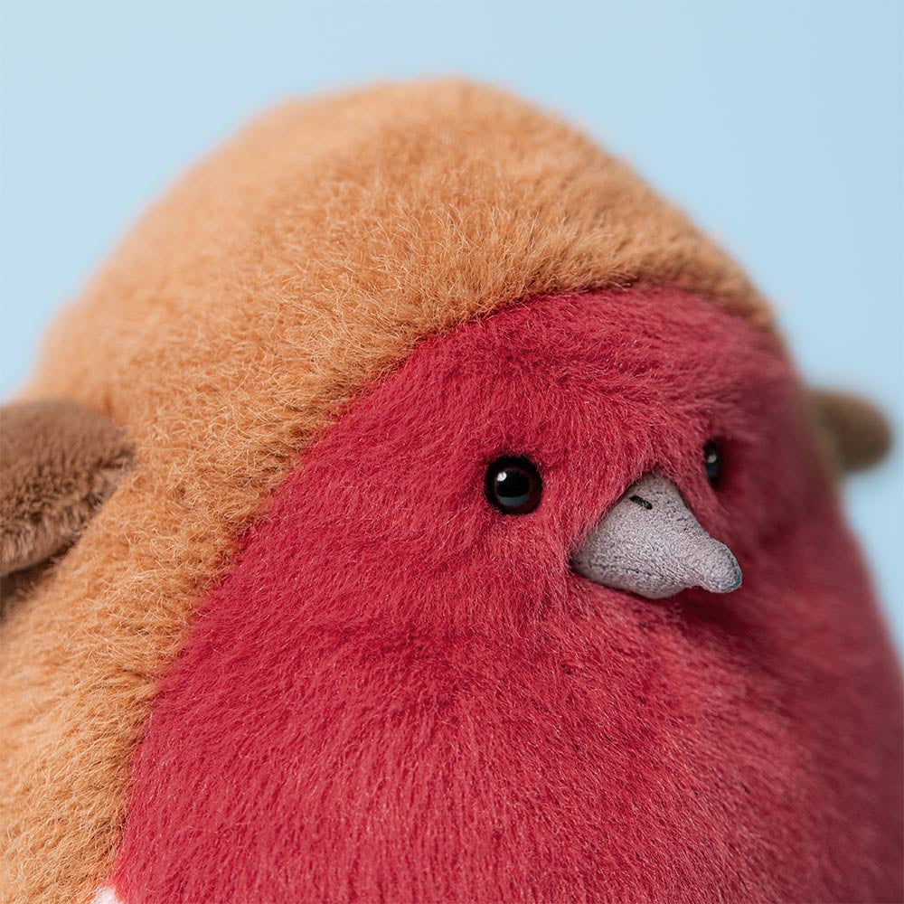 Close-up of a plush toy with a red face and brown body against a light blue background