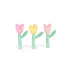 Three small plush tulip-shaped accessories arranged side by side on a plain white background. The left and right pieces are pink with mint green stems and leaves, and the center piece is yellow with a mint green stem and leaves.