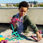A young boy colorful Clixo magnetic play set with packaging on a biege background