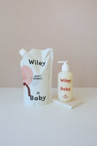 Wiley Baby body bubble refill pouch and pump bottle set on a white surface against a soft beige background.