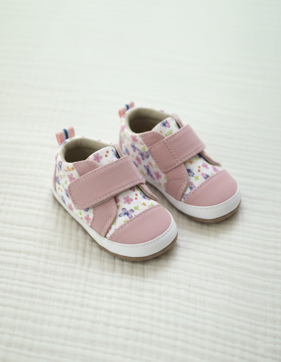 Pair of pink children's shoes with floral pattern on a light background