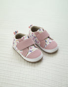 Pair of pink children's shoes with floral pattern on a light background