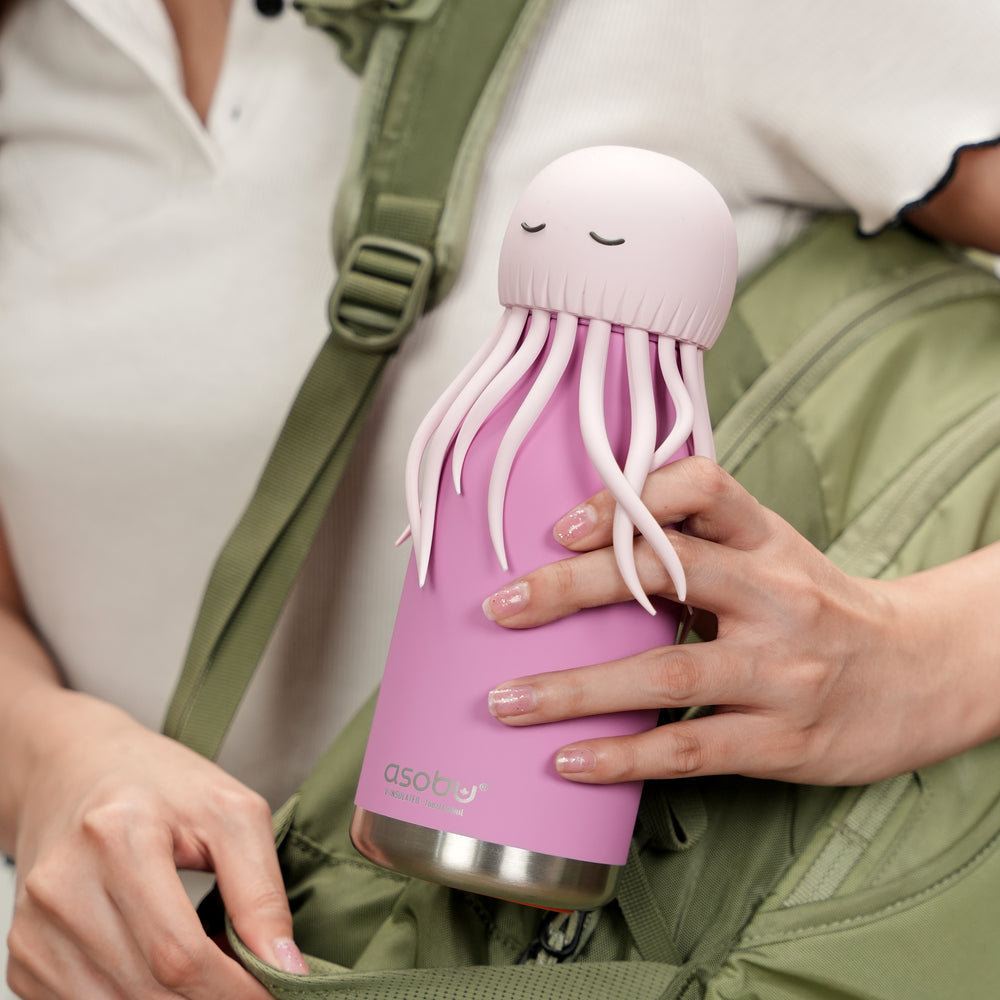 Person holding a pink jellyfish-shaped water bottle with a green backpack