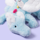 Close-up of a blue plush toy with a tag on a light purple background