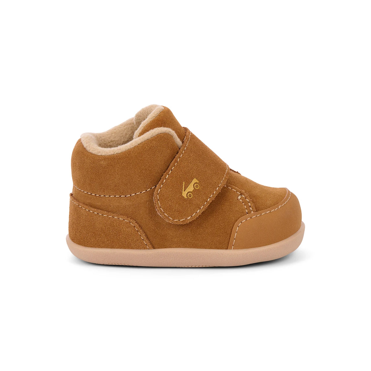 A single toddler bootie in tan suede with a matching tan sole and a light beige fleece lining, featuring a hook-and-loop strap closure with a small gold logo.