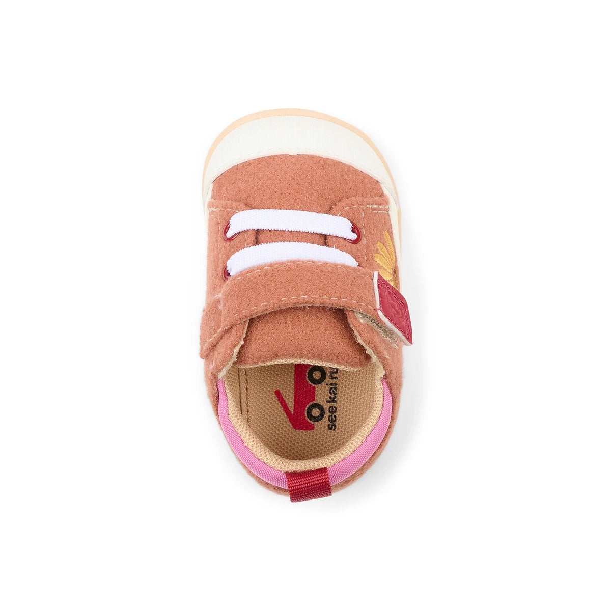 A single baby shoe shown from a top-down view on a white background. The shoe features a dusty rose-brown suede upper with two white hook-and-loop straps, a pink pull tab, a beige fabric footbed, and a white rubber toe cap.