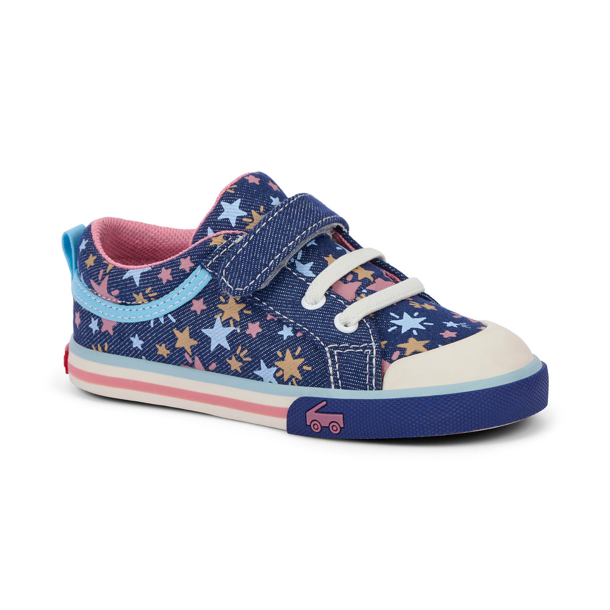 A toddler's blue canvas sneaker with a star pattern, featuring a hook-and-loop strap closure, white laces, a pink interior lining, and a blue, pink, and white striped sole with a small truck graphic on the toe bumper.