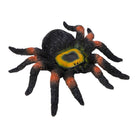 Realistic spider toy with black, orange, and green colors on a white background