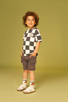 Child wearing a checkered shirt and cargo shorts on a solid background
