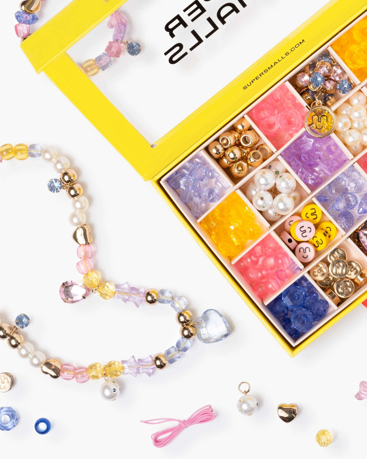 Colorful beaded jewelry set with a box of beads on a white background
