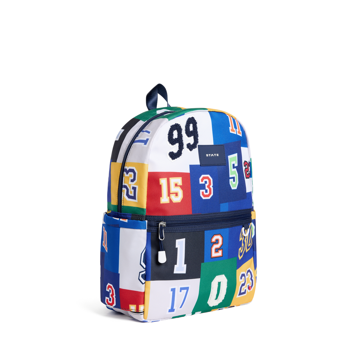 A small backpack featuring an all-over collage of sports jersey panels in multiple colors, including blue, white, red, green, yellow, and black, each with a number. The front pocket has a zipper closure, and a small 'STATE' brand label is visible on the upper front.