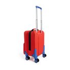 Rear three-quarters view of a red State Bags Mini Logan carry-on suitcase designed to look like a firetruck, showcasing its blue telescopic handle, 360-degree spinner wheels, and black zipper and side pocket details against a transparent background.