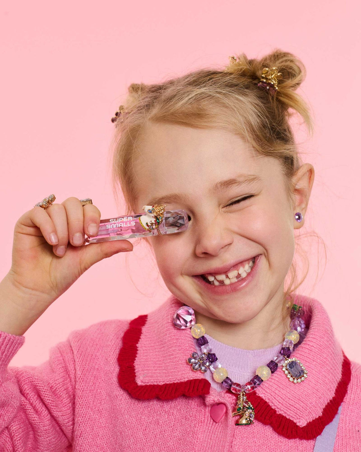 Young girl with a pink lip gloss against a pink background