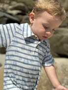 Child wearing a blue and white striped shirt outdoors