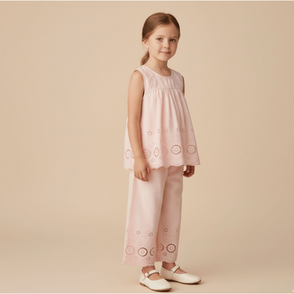 Young girl wearing a pink dress with lace details on a beige background
