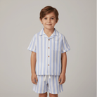 Child wearing a blue and white striped shirt and shorts set on a plain background