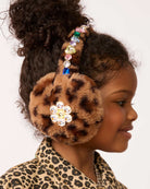A young girl with curly hair wearing plush leopard-print earmuffs.