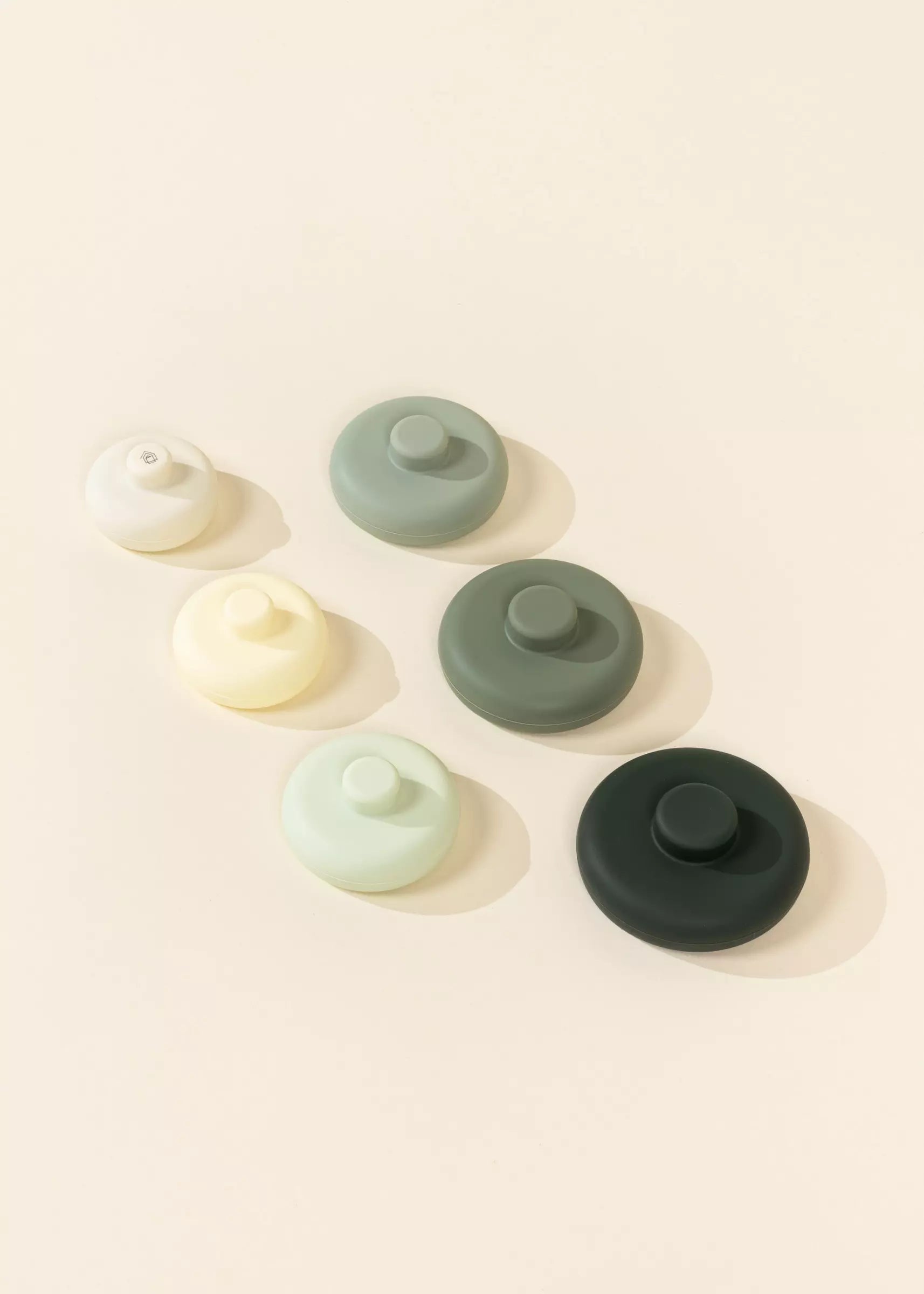 Set of six silicone bottle caps in various colors on a light beige background