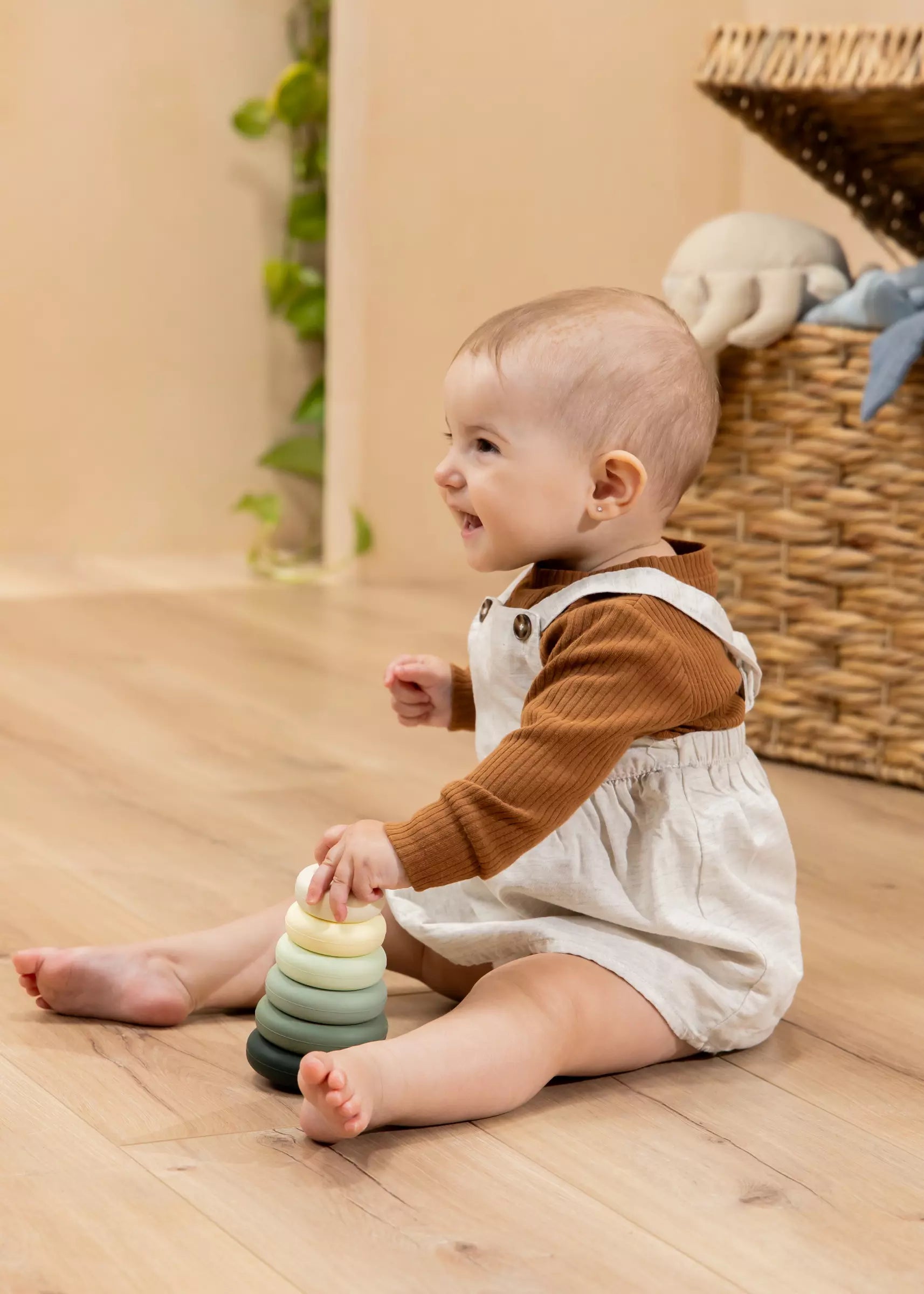 Baby sitting on a wooden floor playing with colorful rings