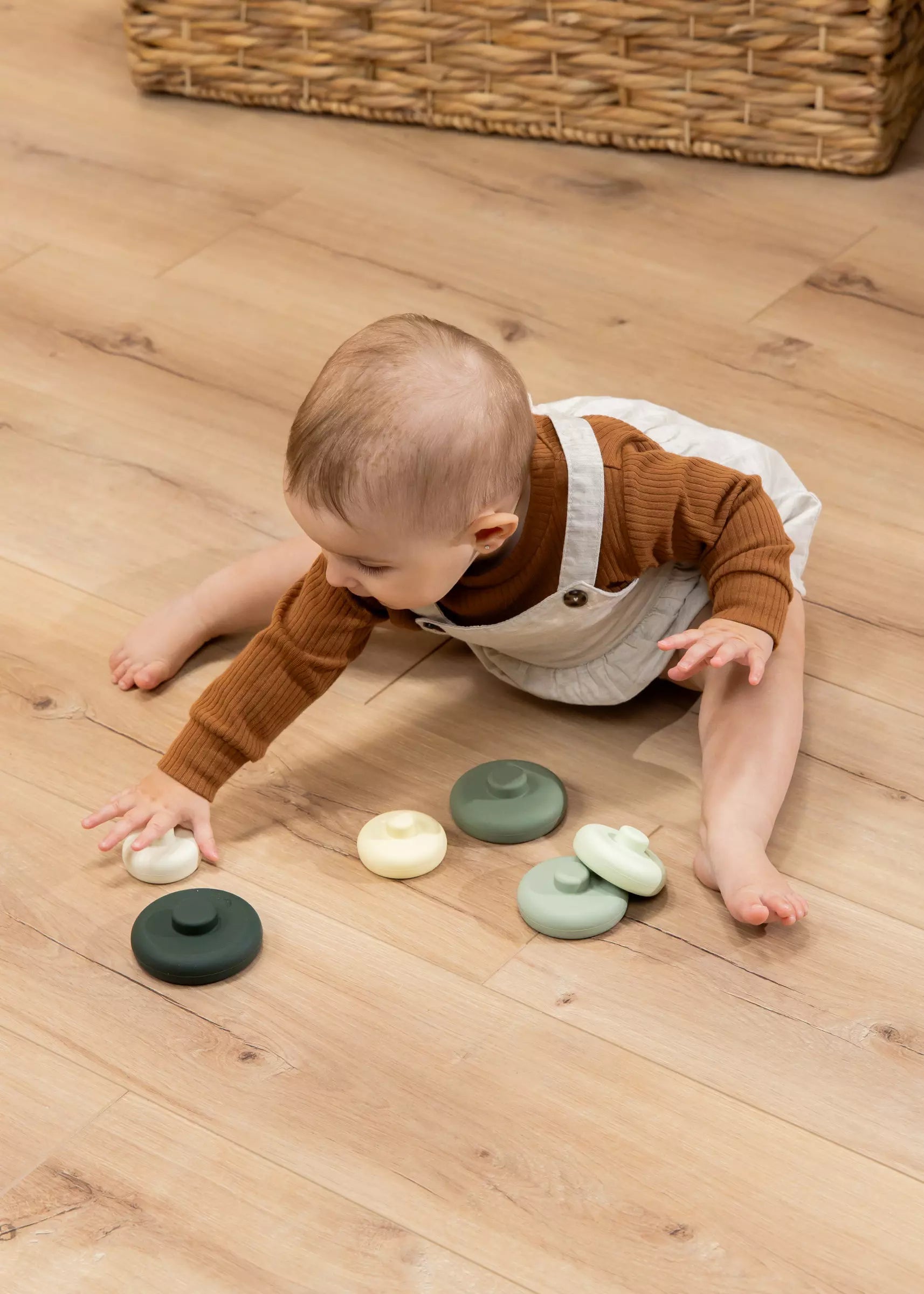 Baby playing with colorful stones on a wooden floor