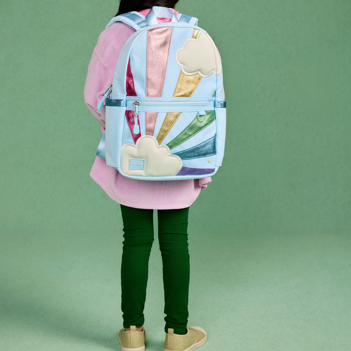 Person wearing a colorful backpack with ice cream cone design on a green background