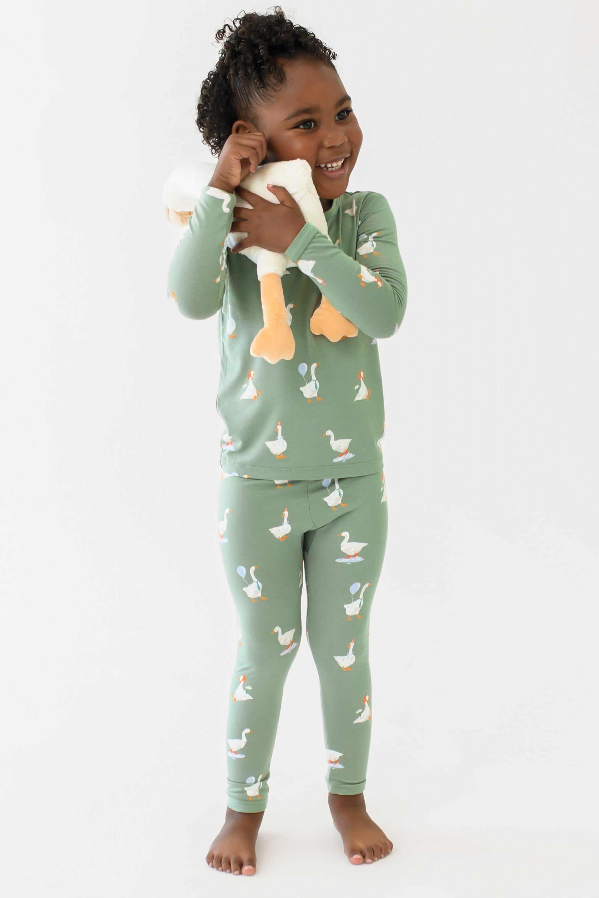 Child wearing green pajamas with duck pattern on a white background