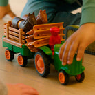 A close-up of a child’s hands playing with the green Smartmax My First Farm Tractor, featuring a brown toy horse and a red driver figure in the front.