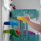 Child's hand interacting with colorful magnetic toy dinosaurs on a refrigerator door.