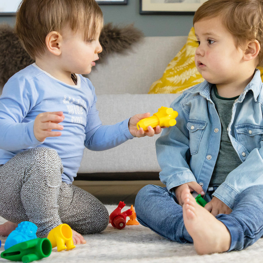 Two young children playing with toys on the floor in a living room.