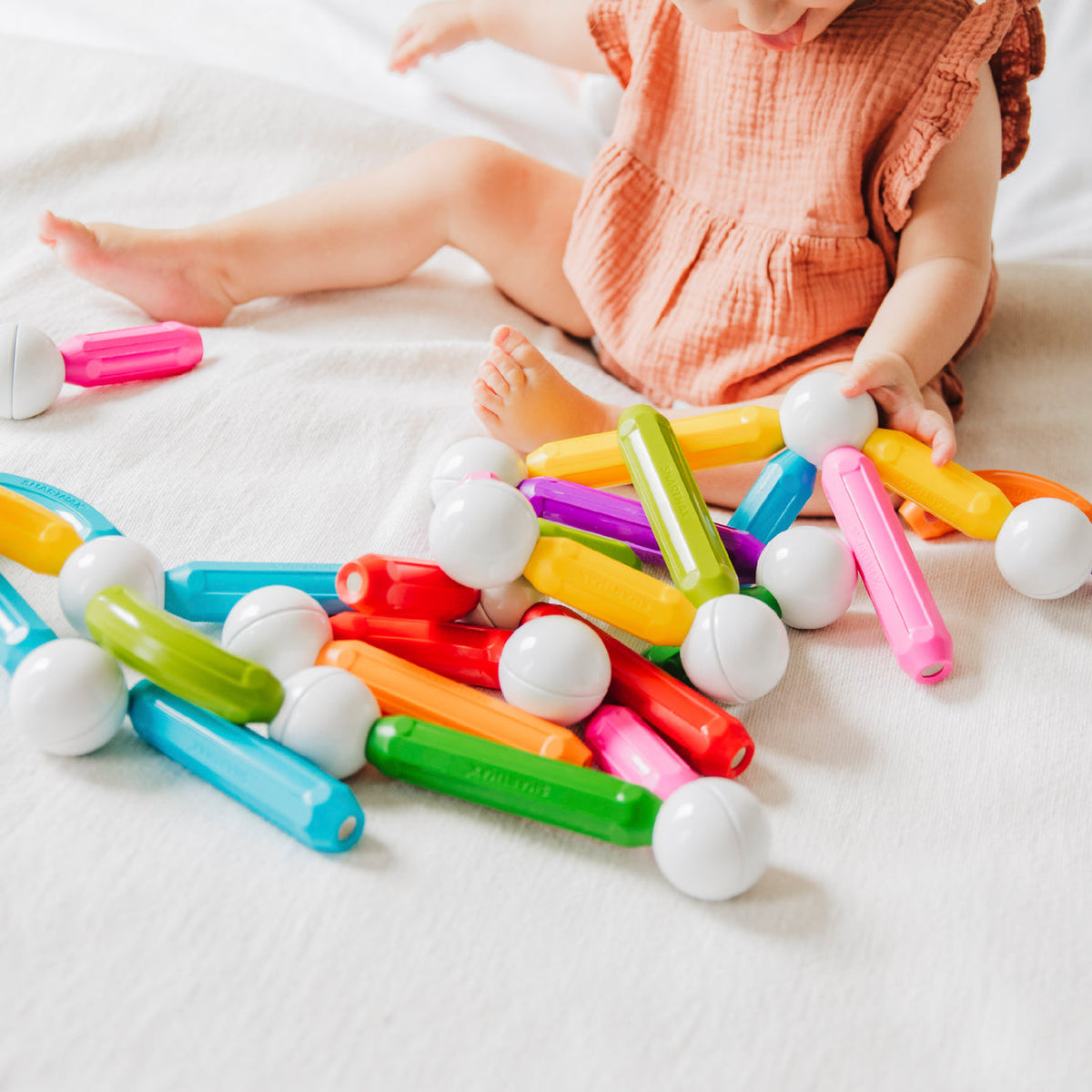 Child playing with colorful building blocks on a white surface