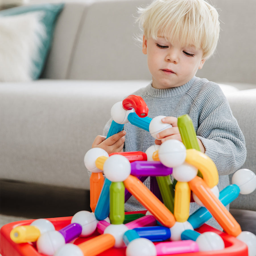 Child playing with colorful building blocks on a couch