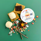 S'mores play set with marshmallows, graham crackers, chocolate bars, and a mini dough kit on a green background.
